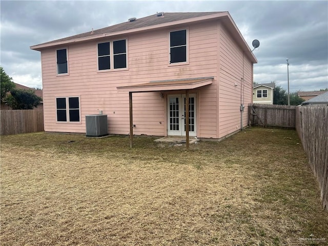 rear view of property featuring a yard and central AC unit