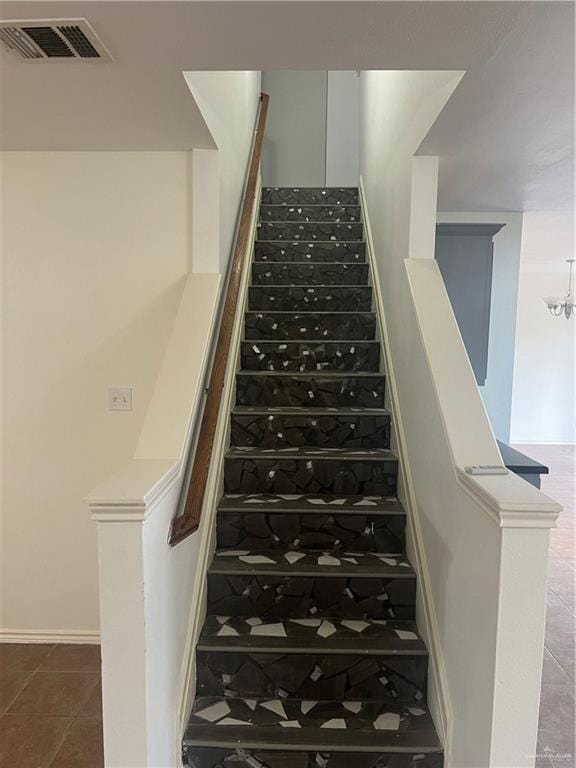 stairs featuring a chandelier and tile patterned floors