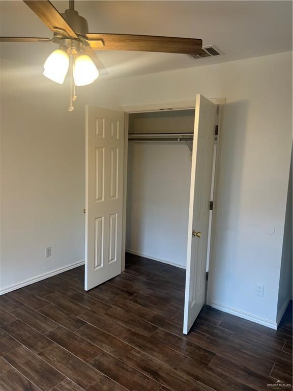 unfurnished bedroom featuring ceiling fan, dark hardwood / wood-style flooring, and a closet