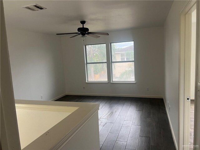 empty room with ceiling fan and dark wood-type flooring