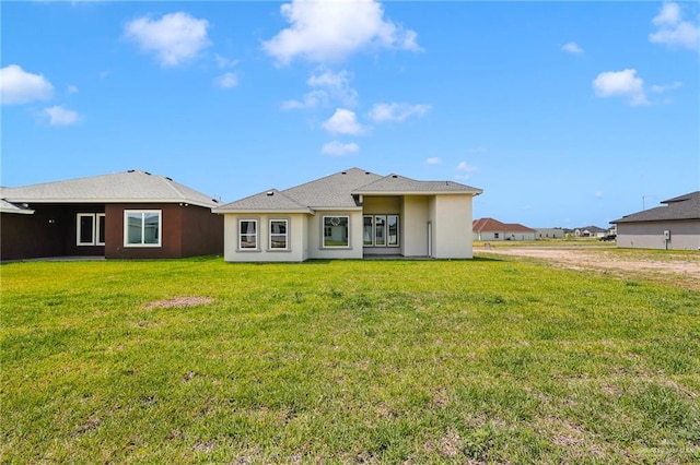 rear view of property featuring a lawn and stucco siding