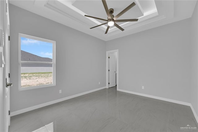 spare room with baseboards, ceiling fan, and a tray ceiling