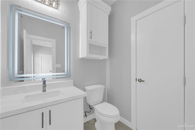 half bath with vanity, baseboards, and toilet