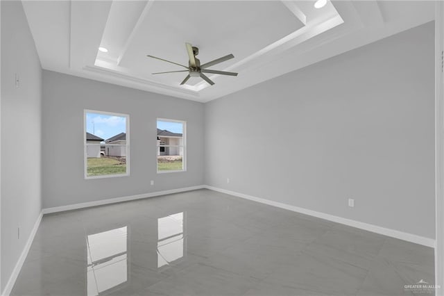 spare room with baseboards, a ceiling fan, and a tray ceiling