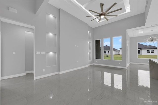 unfurnished living room with baseboards, a ceiling fan, a towering ceiling, and marble finish floor