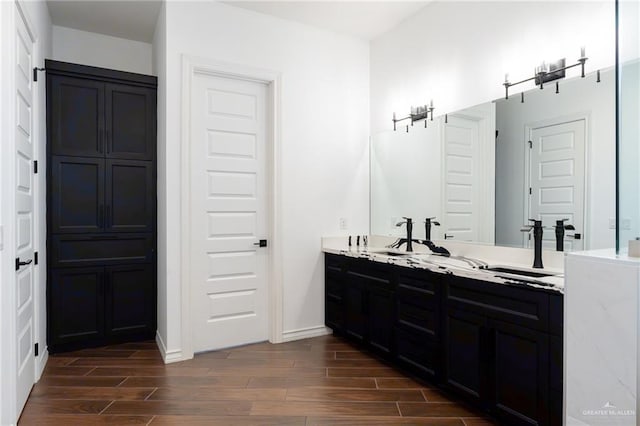 bathroom with wood tiled floor, baseboards, and double vanity