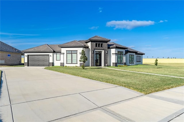 prairie-style home featuring driveway, a front lawn, an attached garage, and stucco siding