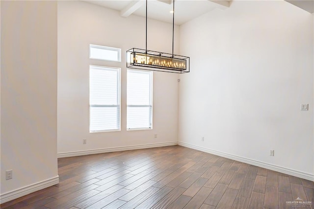 unfurnished dining area featuring wood finished floors, beam ceiling, and baseboards