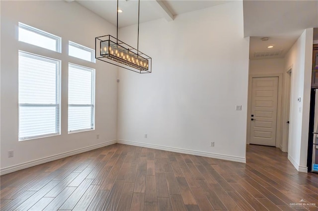 unfurnished dining area with beamed ceiling, dark wood-style flooring, and baseboards