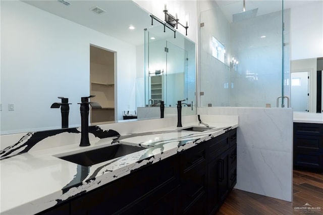 full bathroom with double vanity, a stall shower, visible vents, and wood finished floors