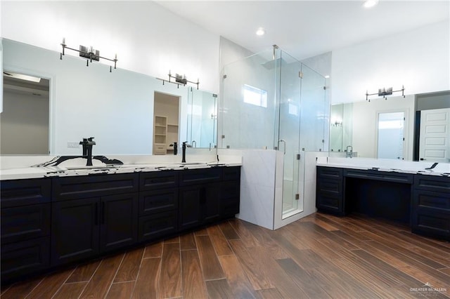 bathroom featuring a sink, double vanity, a stall shower, and wood finished floors