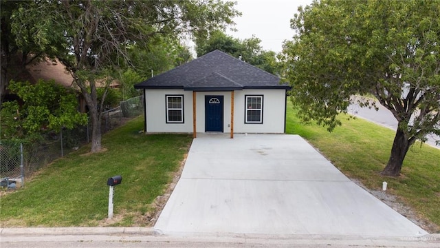 bungalow-style home featuring a shingled roof, a front lawn, and fence