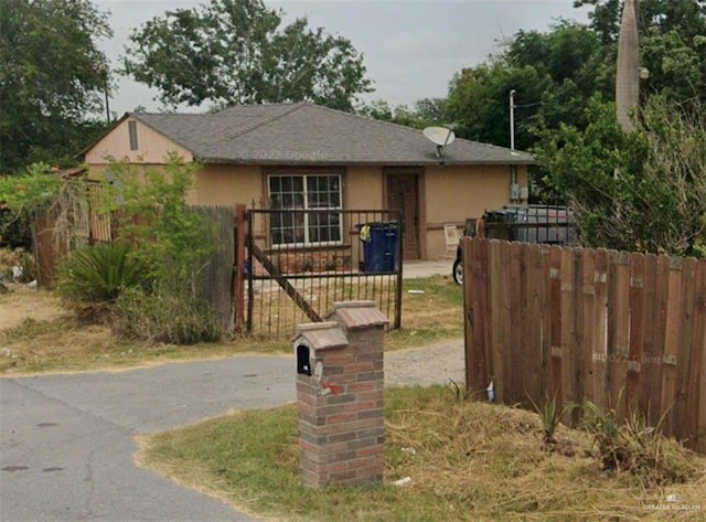 view of front of home featuring fence, driveway, and stucco siding