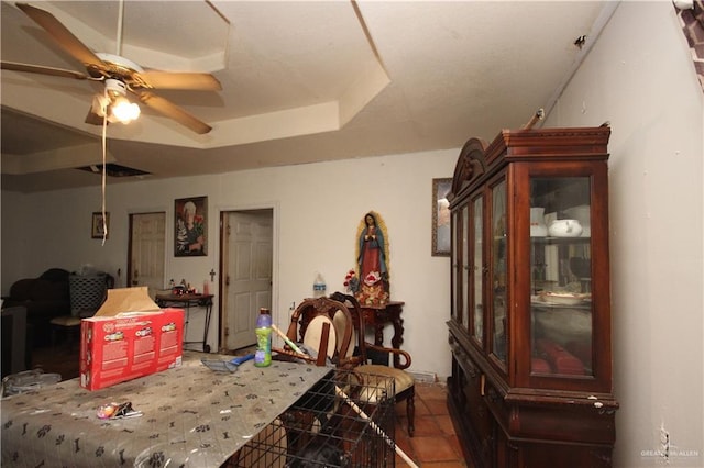 interior space with a raised ceiling, ceiling fan, and tile patterned flooring