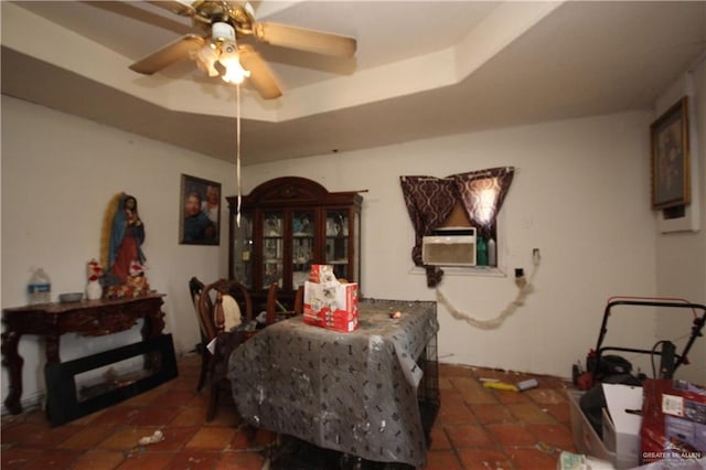 tiled dining space featuring cooling unit, a raised ceiling, and a ceiling fan