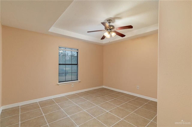 unfurnished room featuring a tray ceiling, ceiling fan, and light tile patterned flooring