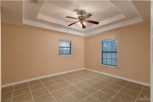 spare room featuring plenty of natural light, ceiling fan, and a tray ceiling