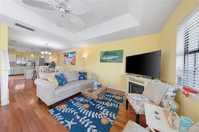 210 W Oleander St Unit B, South Padre Island, TX 78597 - living area featuring light wood finished floors, a raised ceiling, a chandelier, and a ceiling fan
