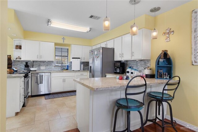 210 W Oleander St Unit B, South Padre Island, TX 78597 - kitchen with stainless steel appliances, a peninsula, backsplash, white cabinetry, and open shelves