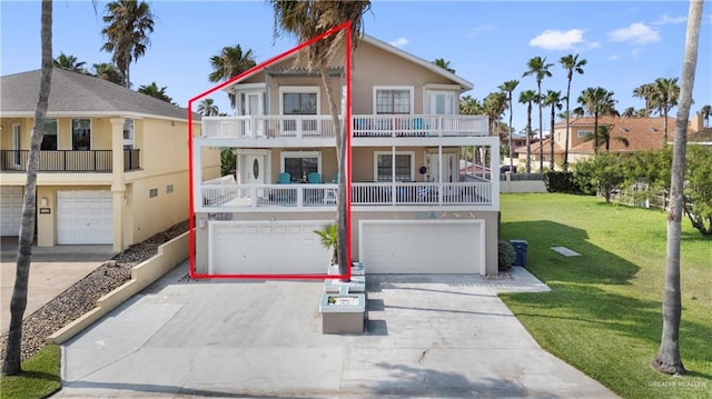 210 W Oleander St Unit B, South Padre Island, TX 78597 - view of front of house with a garage, a balcony, stucco siding, driveway, and a front lawn