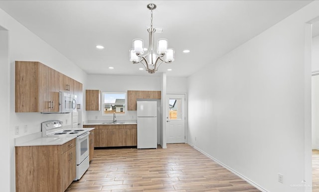 kitchen featuring white appliances, sink, hanging light fixtures, light hardwood / wood-style floors, and a chandelier