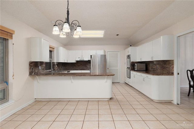 kitchen featuring appliances with stainless steel finishes, a peninsula, a breakfast bar area, and light tile patterned floors