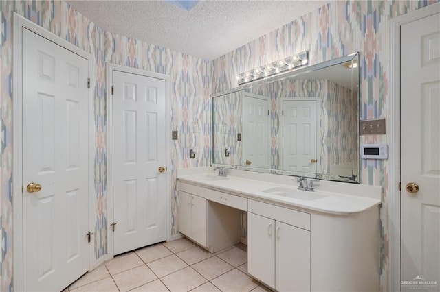 full bath with a sink, a textured ceiling, and wallpapered walls