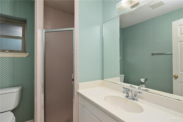 bathroom with a stall shower, visible vents, toilet, a textured ceiling, and vanity