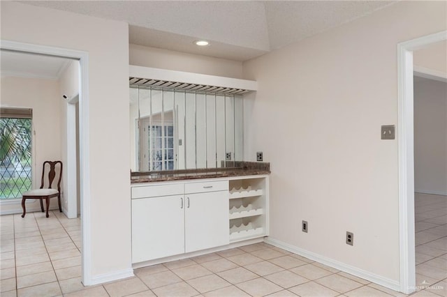 kitchen featuring dark countertops, white cabinets, baseboards, and light tile patterned floors