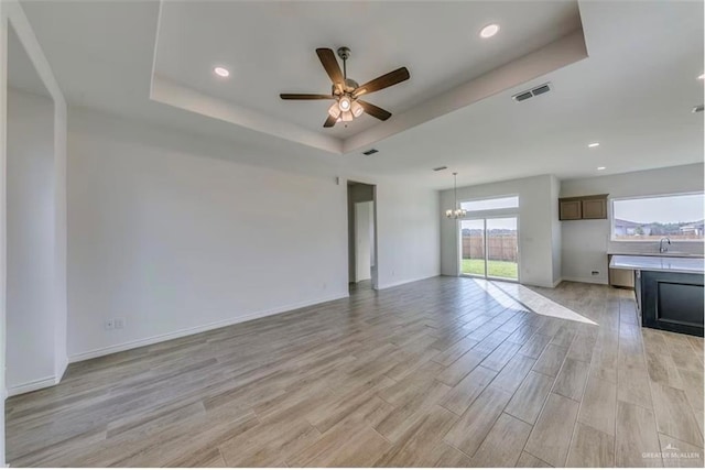 7409 55th St, Mcallen, TX 78573 - unfurnished living room with ceiling fan, a tray ceiling, light wood-style floors, a chandelier, and recessed lighting