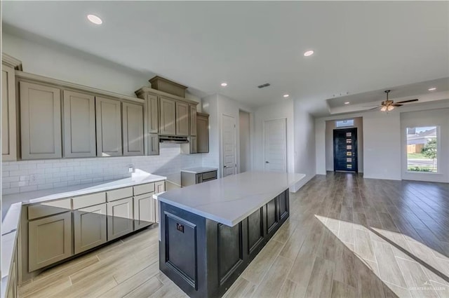 7409 55th St, Mcallen, TX 78573 - kitchen with light wood finished floors, decorative backsplash, recessed lighting, a center island, and under cabinet range hood