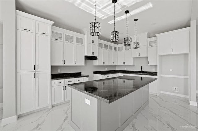 kitchen featuring baseboards, glass insert cabinets, a kitchen island, under cabinet range hood, and marble finish floor