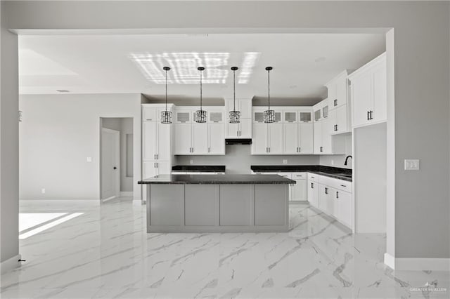 kitchen with glass insert cabinets, baseboards, dark countertops, and marble finish floor