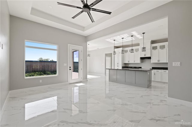 kitchen with baseboards, open floor plan, white cabinetry, dark countertops, and marble finish floor