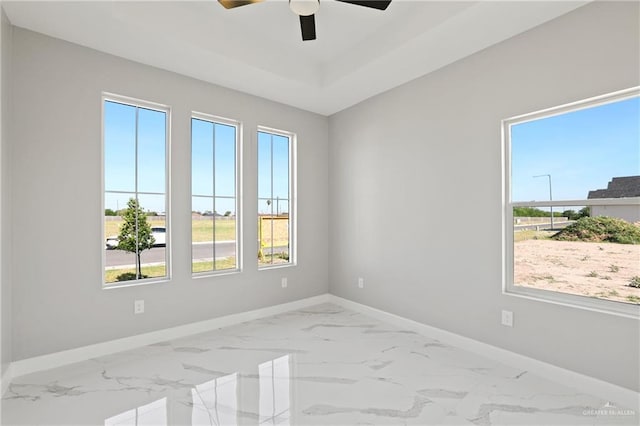 unfurnished room featuring ceiling fan, marble finish floor, and baseboards