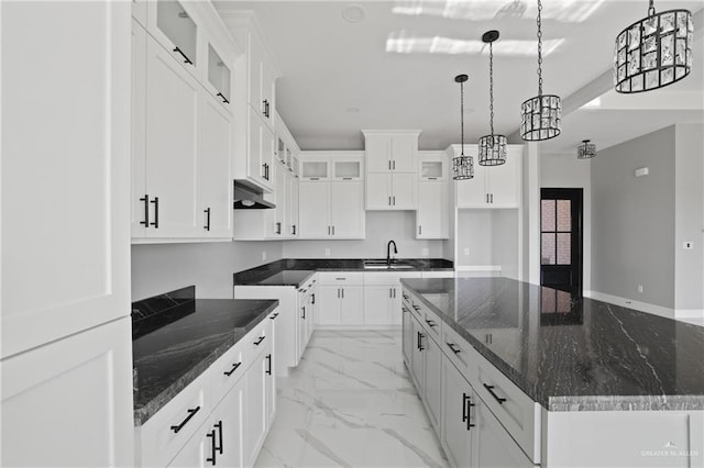 kitchen featuring glass insert cabinets, a large island, a sink, under cabinet range hood, and marble finish floor
