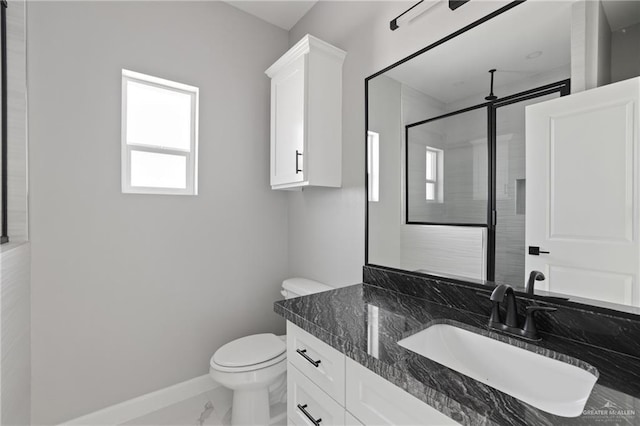 bathroom featuring vanity, toilet, marble finish floor, a stall shower, and baseboards