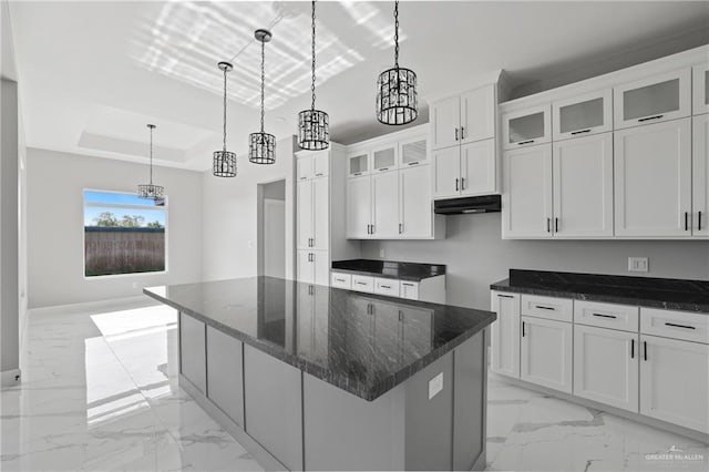 kitchen with a center island, marble finish floor, a chandelier, and under cabinet range hood