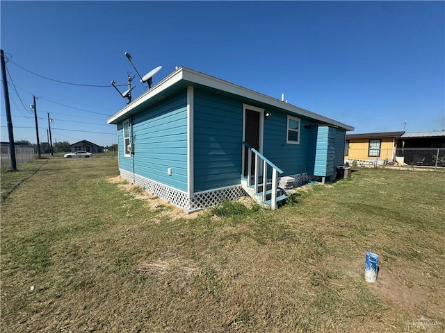 back of property with a lawn, entry steps, and fence