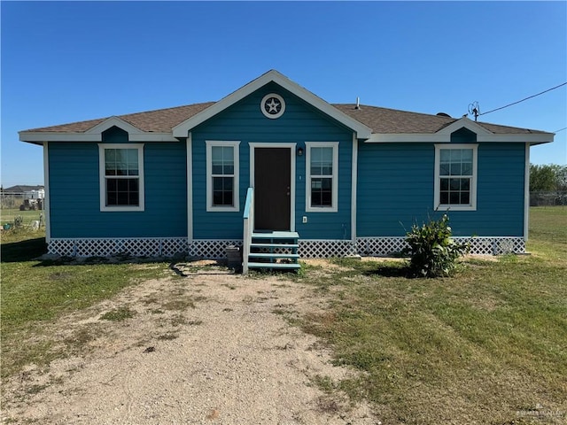 view of front of home with entry steps, a front yard, and roof with shingles