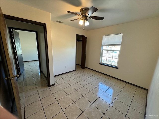 empty room featuring ceiling fan, visible vents, baseboards, and light tile patterned flooring