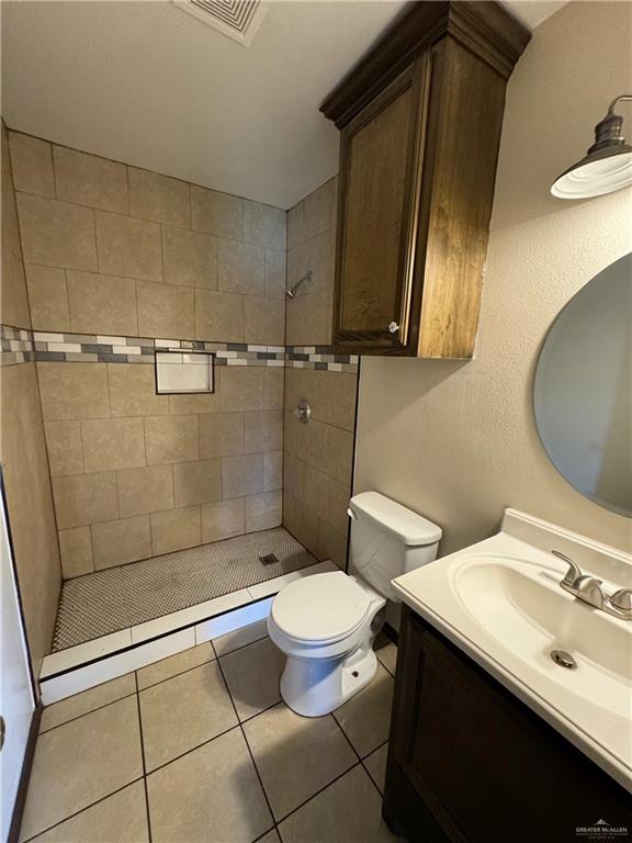 bathroom featuring visible vents, toilet, a stall shower, and vanity