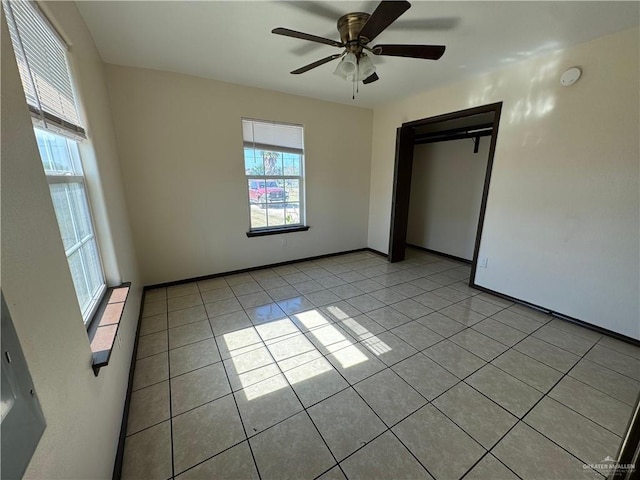 unfurnished bedroom with light tile patterned floors, a closet, multiple windows, and a ceiling fan