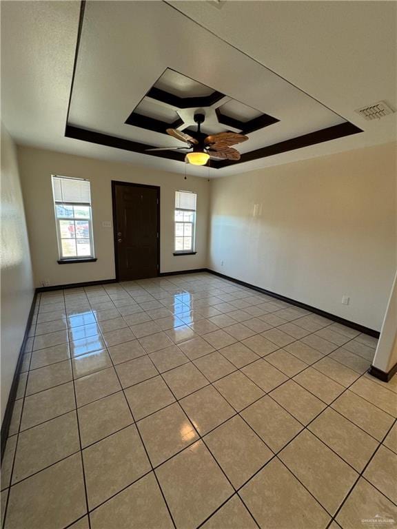 spare room with a raised ceiling, light tile patterned floors, a ceiling fan, and baseboards