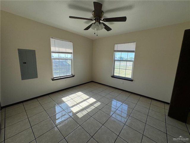 spare room with electric panel, light tile patterned floors, a healthy amount of sunlight, and baseboards