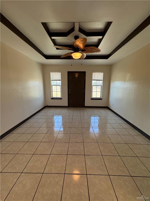 entrance foyer featuring light tile patterned flooring, a healthy amount of sunlight, baseboards, and a tray ceiling