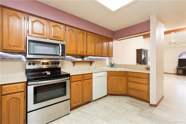 kitchen featuring kitchen peninsula, ceiling fan, sink, and stainless steel appliances