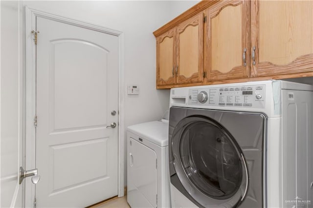 laundry room with separate washer and dryer and cabinets