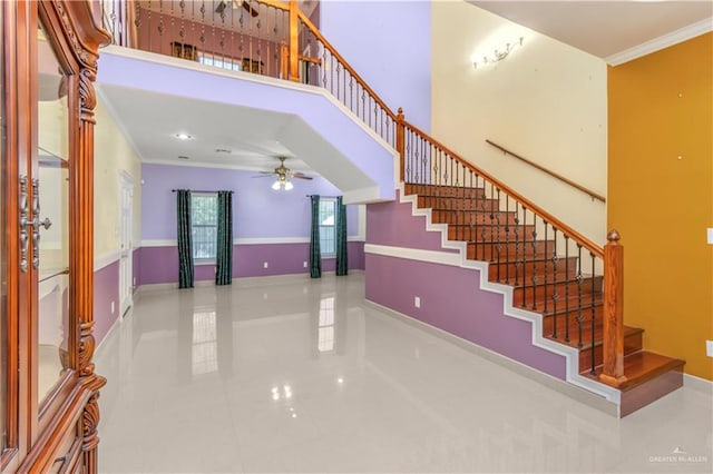 tiled foyer entrance with a towering ceiling, ceiling fan, and ornamental molding