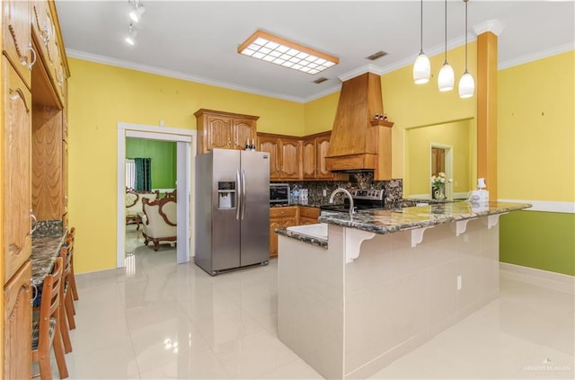 kitchen with dark stone countertops, kitchen peninsula, pendant lighting, appliances with stainless steel finishes, and ornamental molding